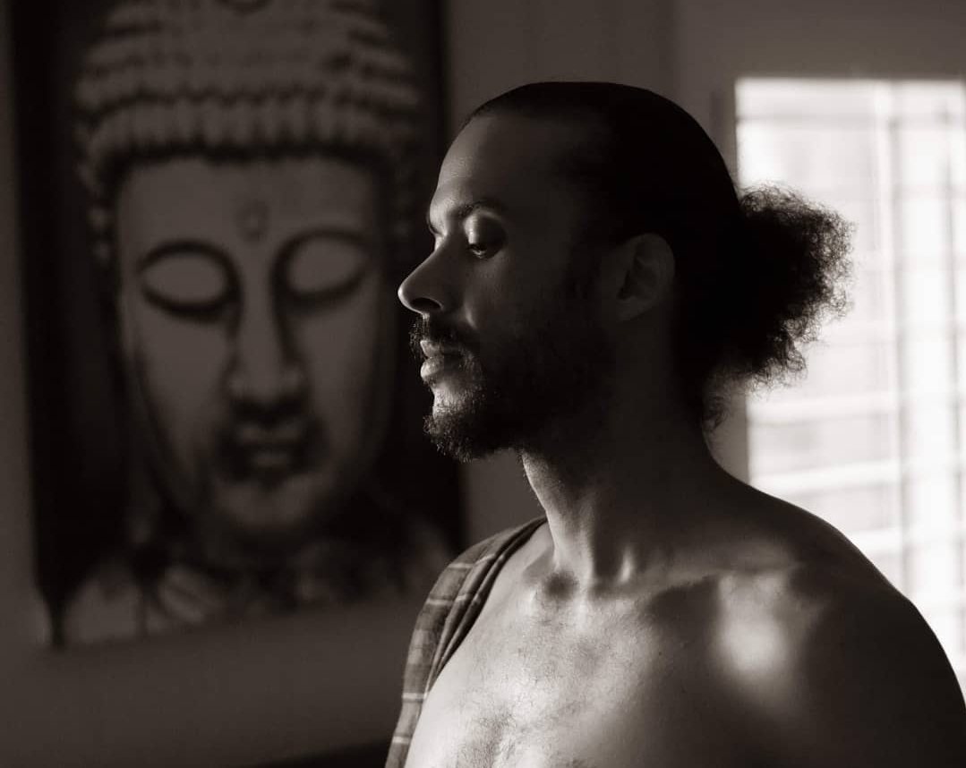 A man in profile before a Buddha image